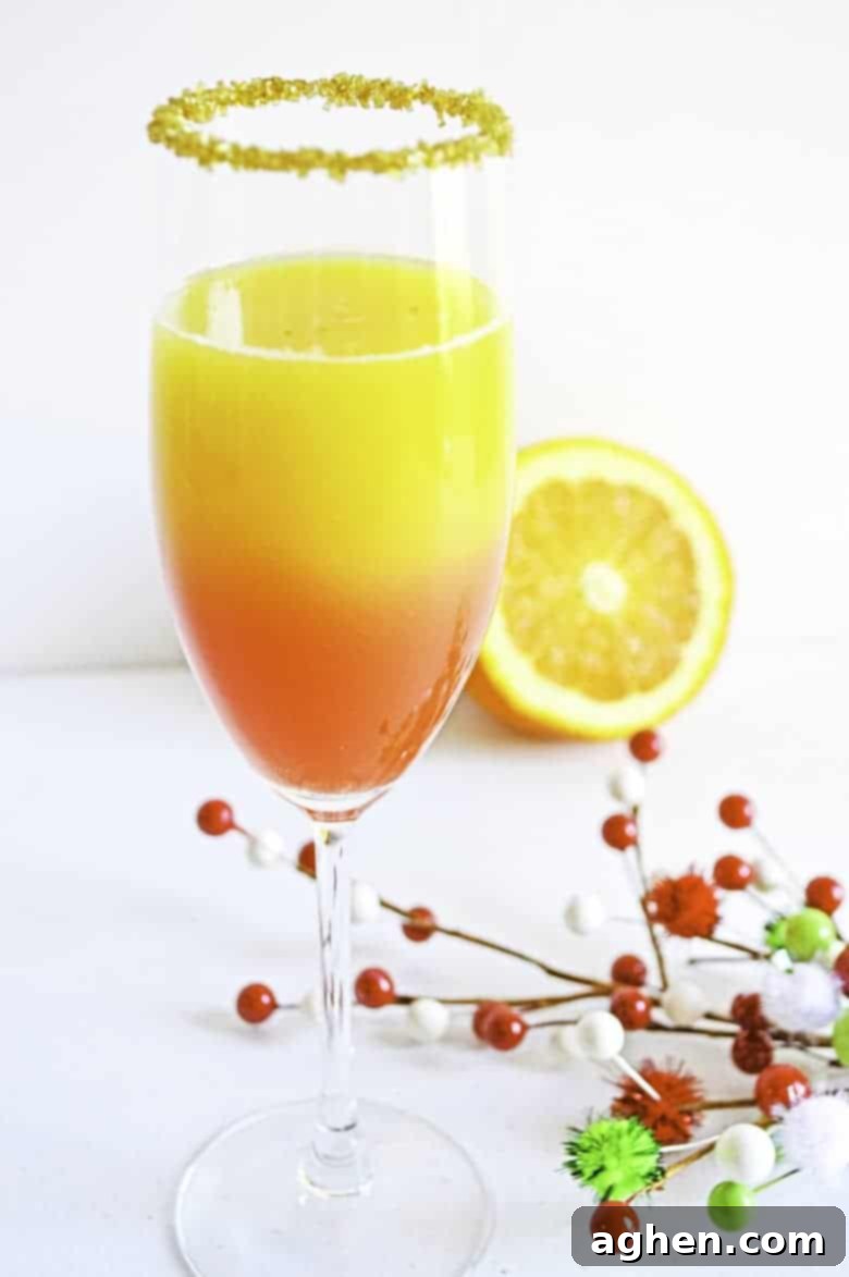 Christmas Mimosa Recipe in cocktail glass, garnished with orange slice and sprinkles
