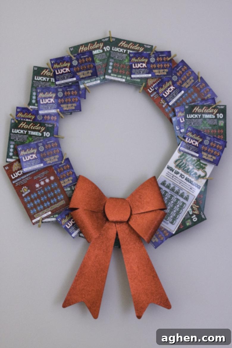 Lottery ticket wreath with a large red box hanging on a wall, showcasing a unique and festive gift idea made with scratch-off tickets.