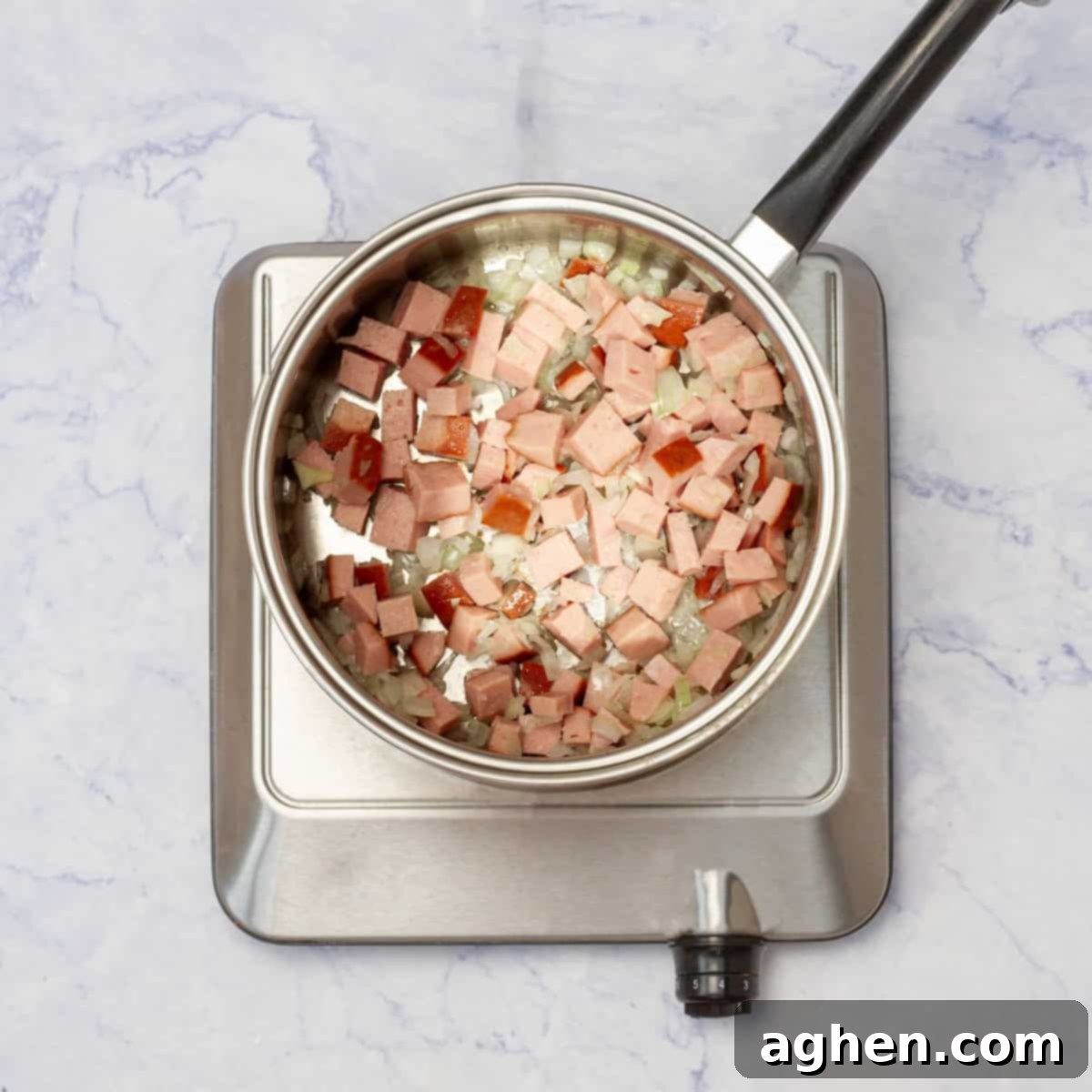 Finely chopped onions and diced turkey ham browning in a pan on the stove.