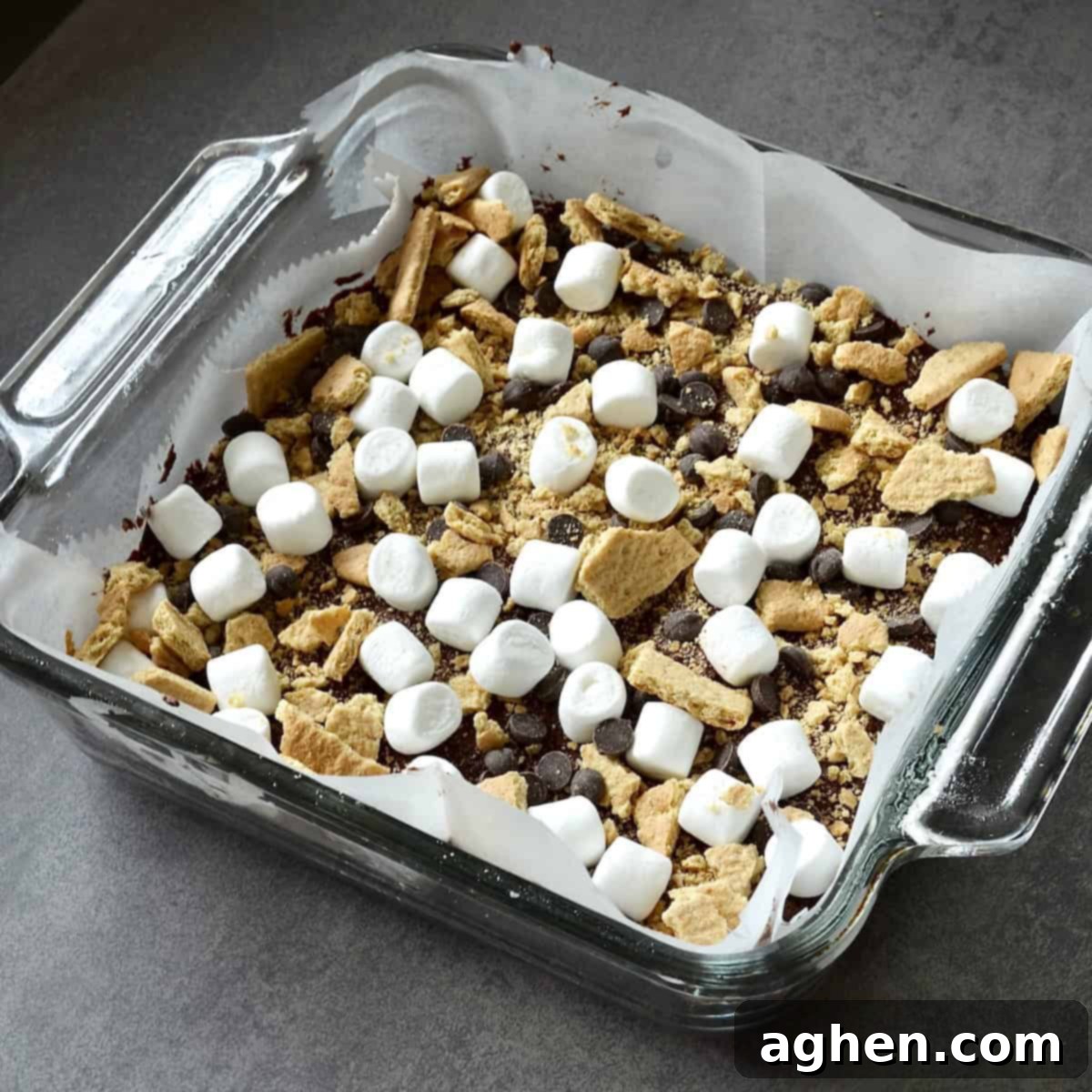 S'mores brownies before baking, topped with mini marshmallows, chocolate chips, and graham cracker crumbs