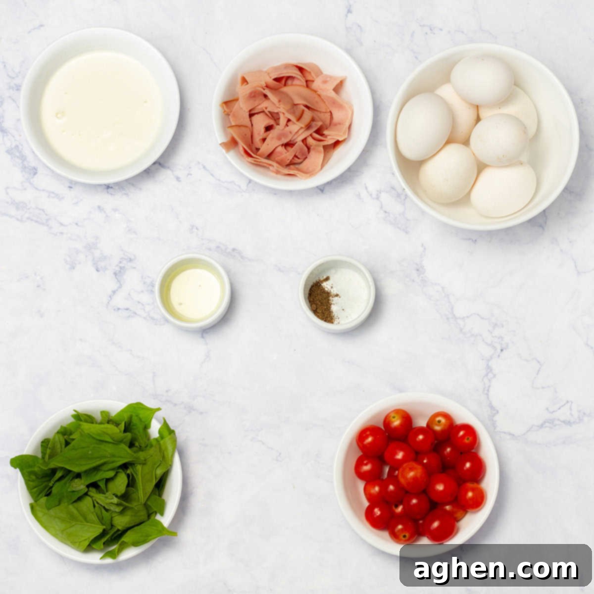 Various frittata ingredients laid out: eggs, sliced turkey ham, cherry tomatoes, spinach, and spices.