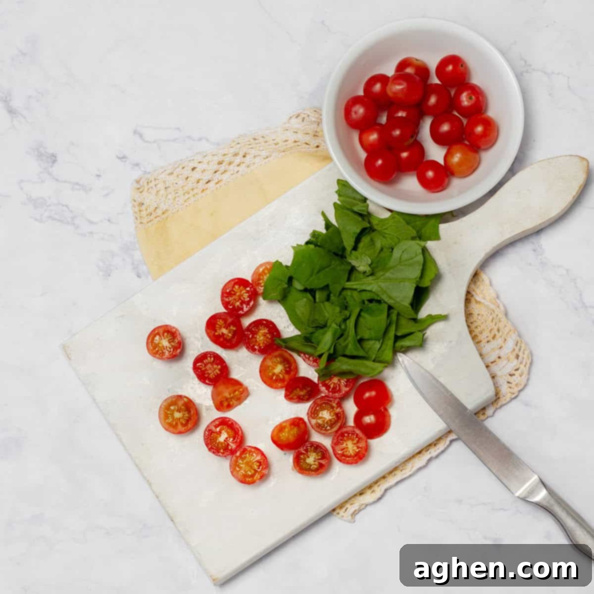 Cherry tomatoes and fresh herbs being chopped on a wooden cutting board.