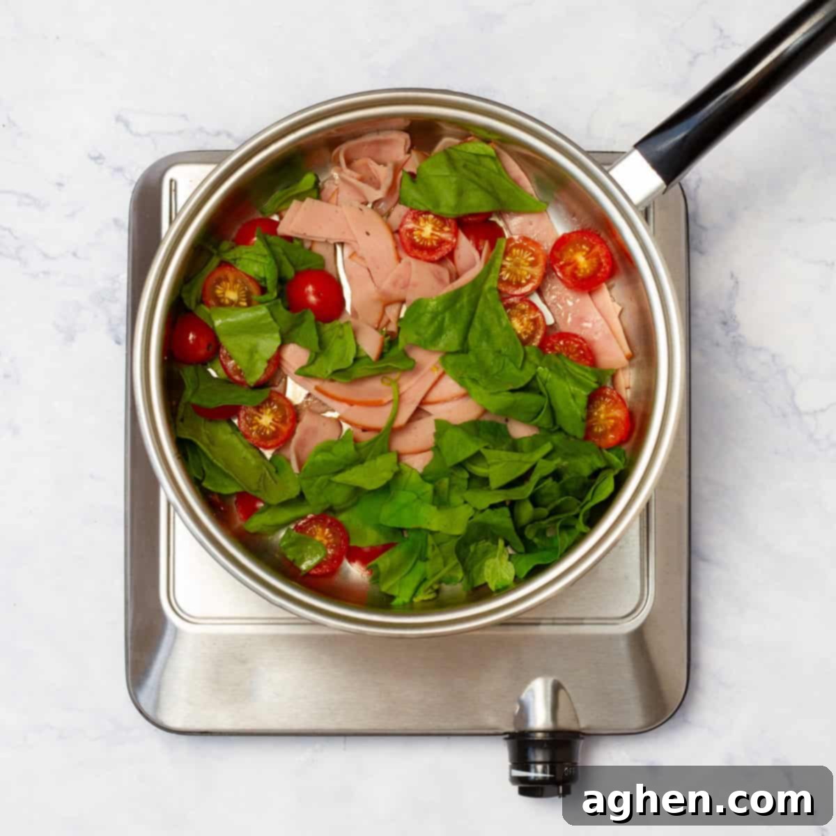 Prepped vegetables and chopped turkey ham cooking in a hot skillet on the stove.