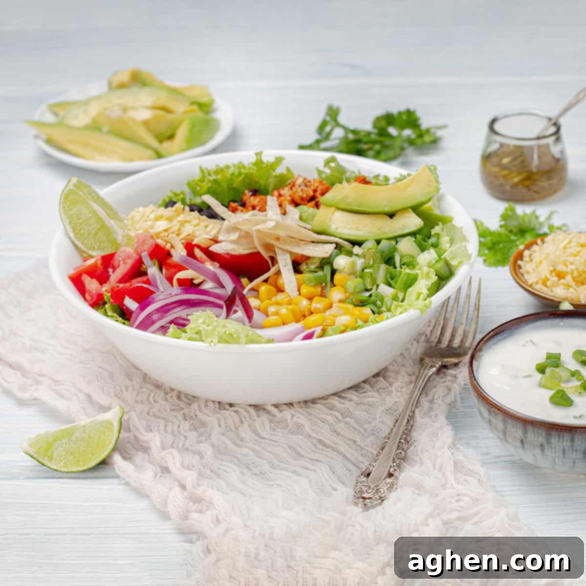 A vibrant bowl of ultimate turkey taco salad, generously loaded with fresh vegetables, seasoned ground turkey, black beans, and a creamy cilantro-lime dressing, garnished with fresh lime wedges on the side.