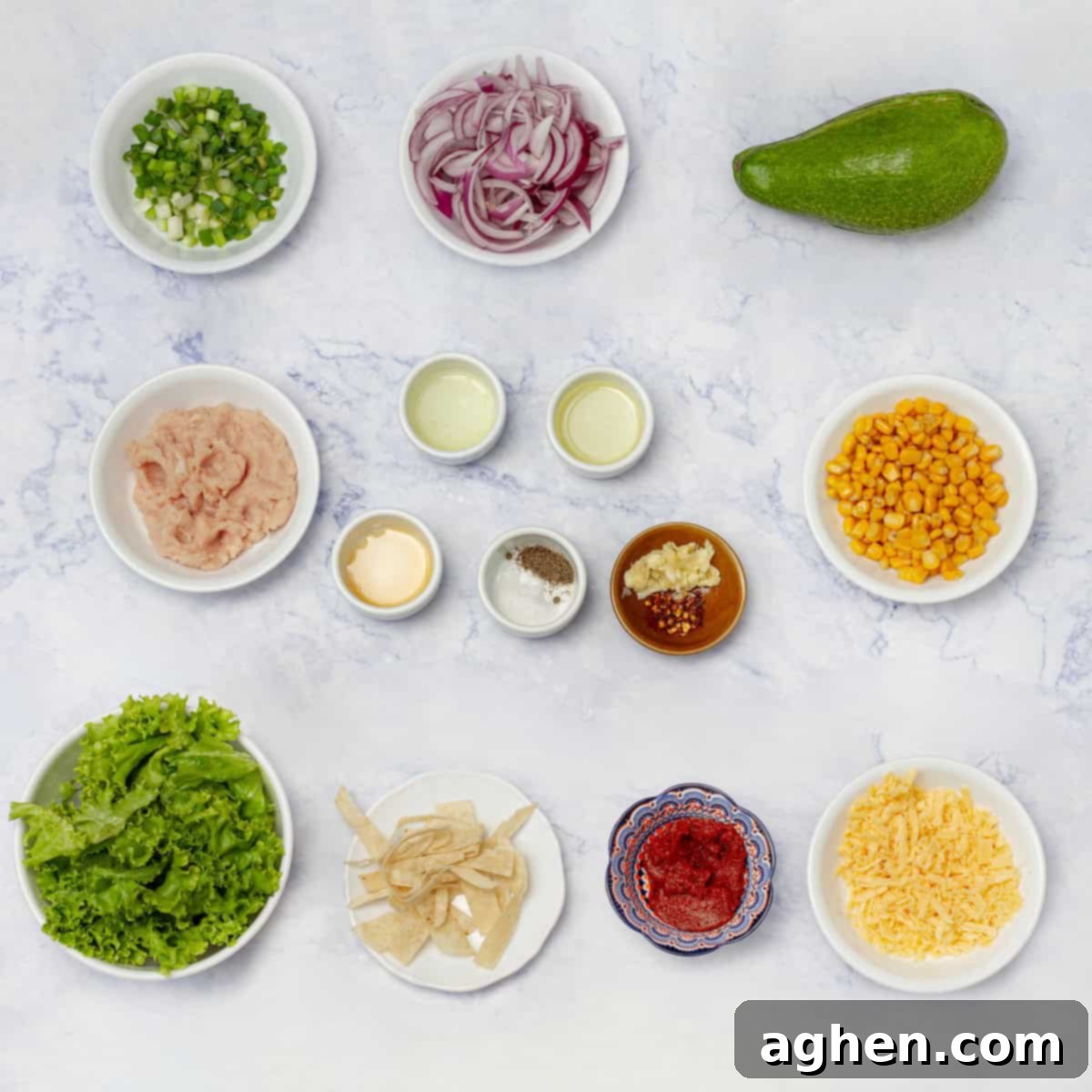 All the fresh ingredients for the ultimate turkey taco salad laid out on a kitchen counter in separate bowls and dishes, including ground turkey, fresh vegetables, and dressing components.