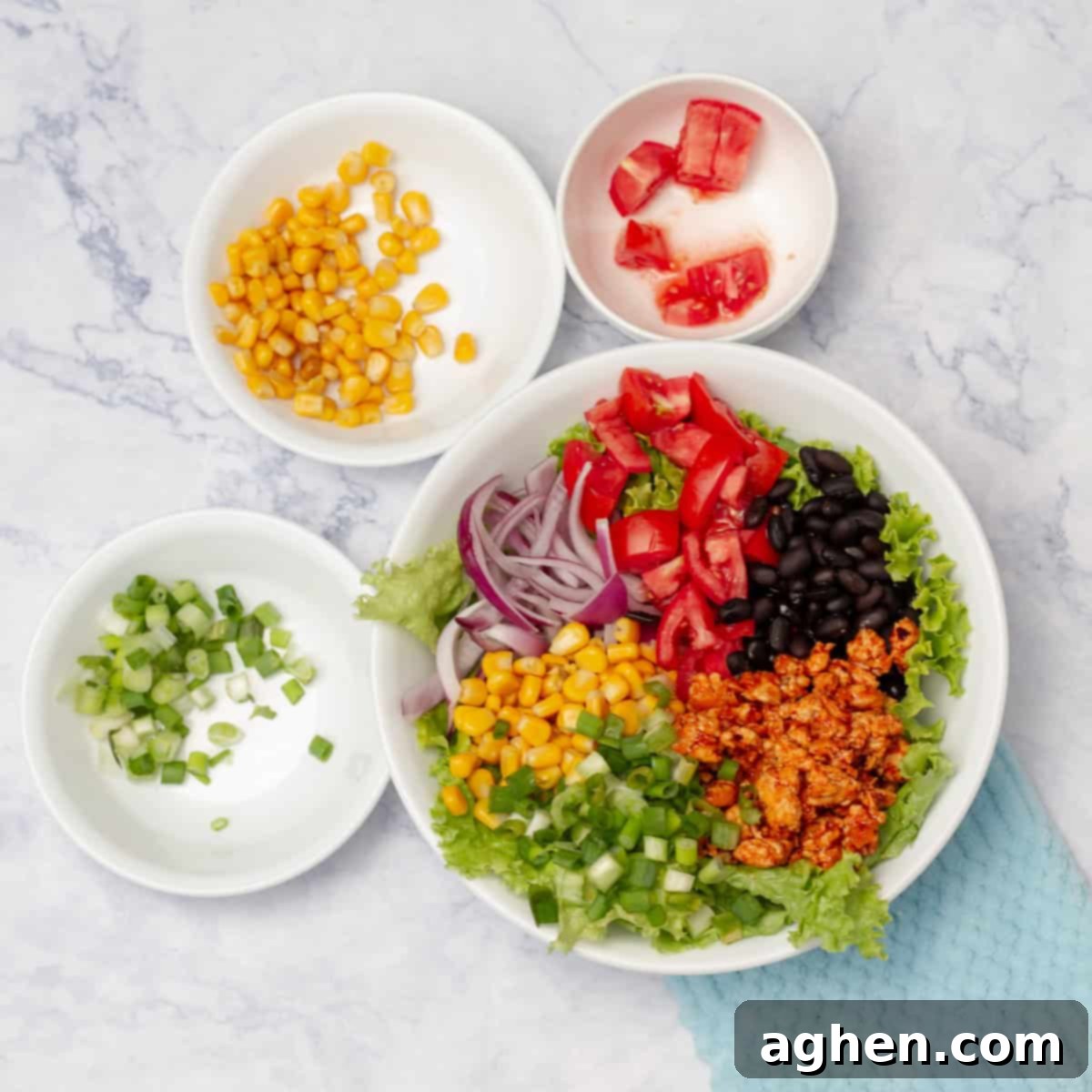 A large, colorful turkey taco salad being assembled in a bowl, with layers of lettuce, vegetables, ground turkey, and avocado visible before the dressing is added.