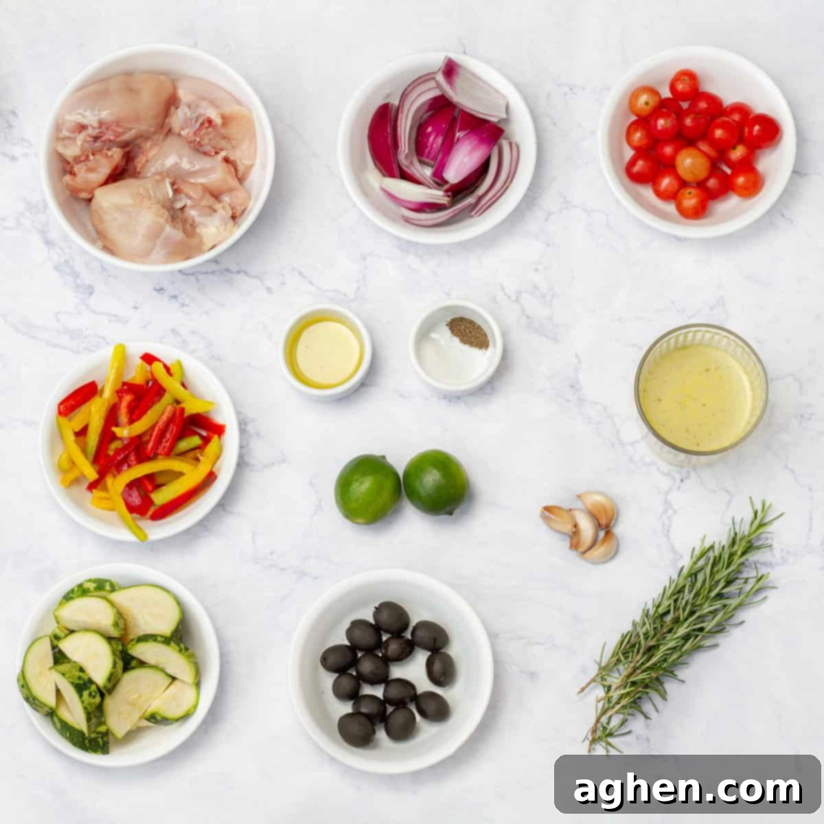 Yunan Limonlu Tavuk: Diyette Olanlar İçin İdeal Yaz Akşamı 3 Greek Lemon Chicken ingredients of chicken breast, tomatoes, bell pepper, zucchini, olives, limes, garlic, sprigs, and and oil in separate dishes on a counter.