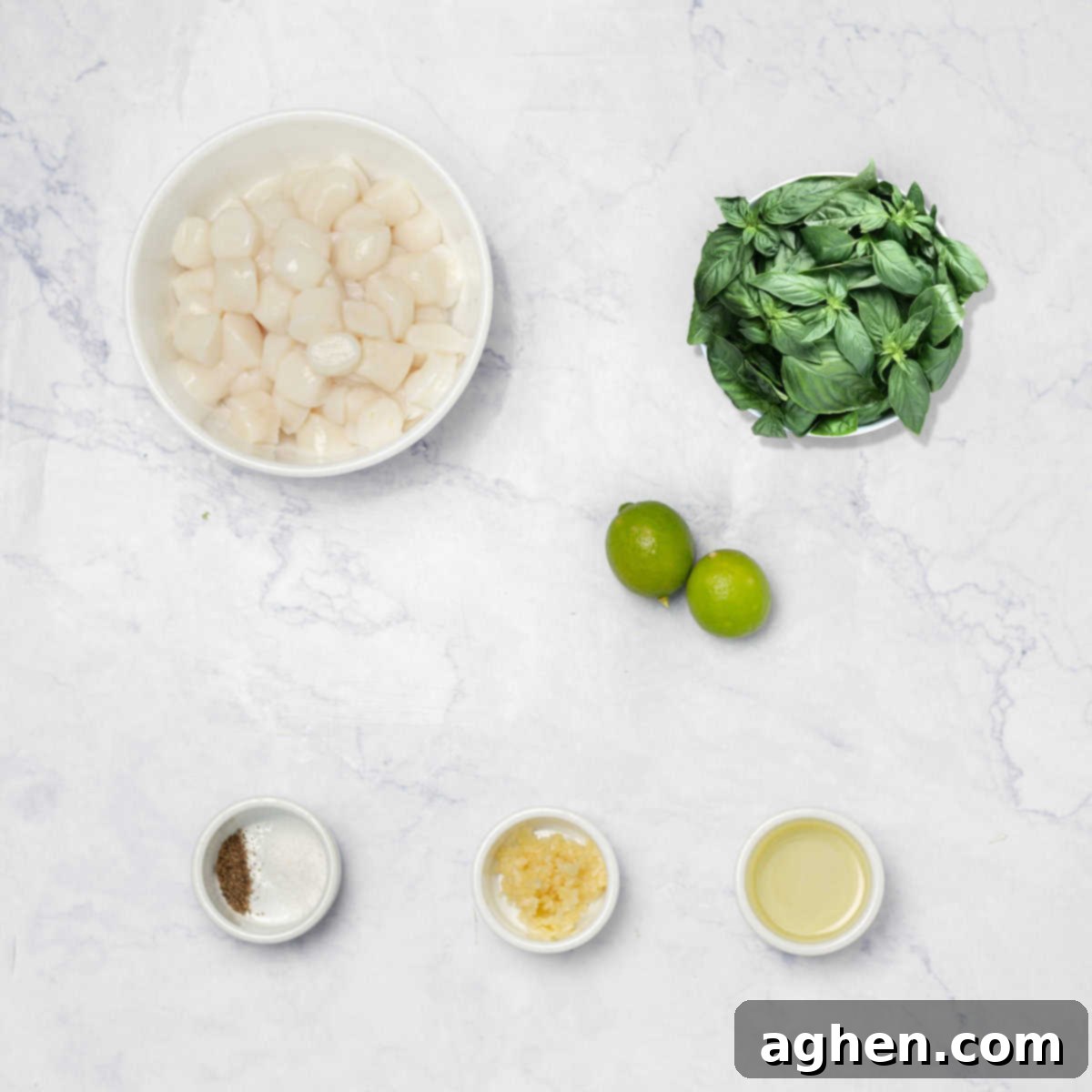 Ingredients for seared scallops including fresh basil, lemons, minced garlic, olive oil, and raw scallops in separate bowls.