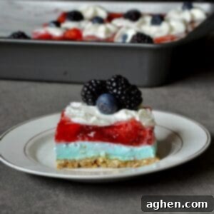 Guilt-Free 2-Point 4th of July Strawberry Pretzel Salad 7 A slice of 4th of July Strawberry Pretzel Salad with layers of pretzel crust, blue cheesecake filling, and red strawberry jello.