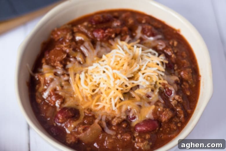 Ultimate Slow Cooker Chili 6 Bowl of beef chili with shredded cheese on top.