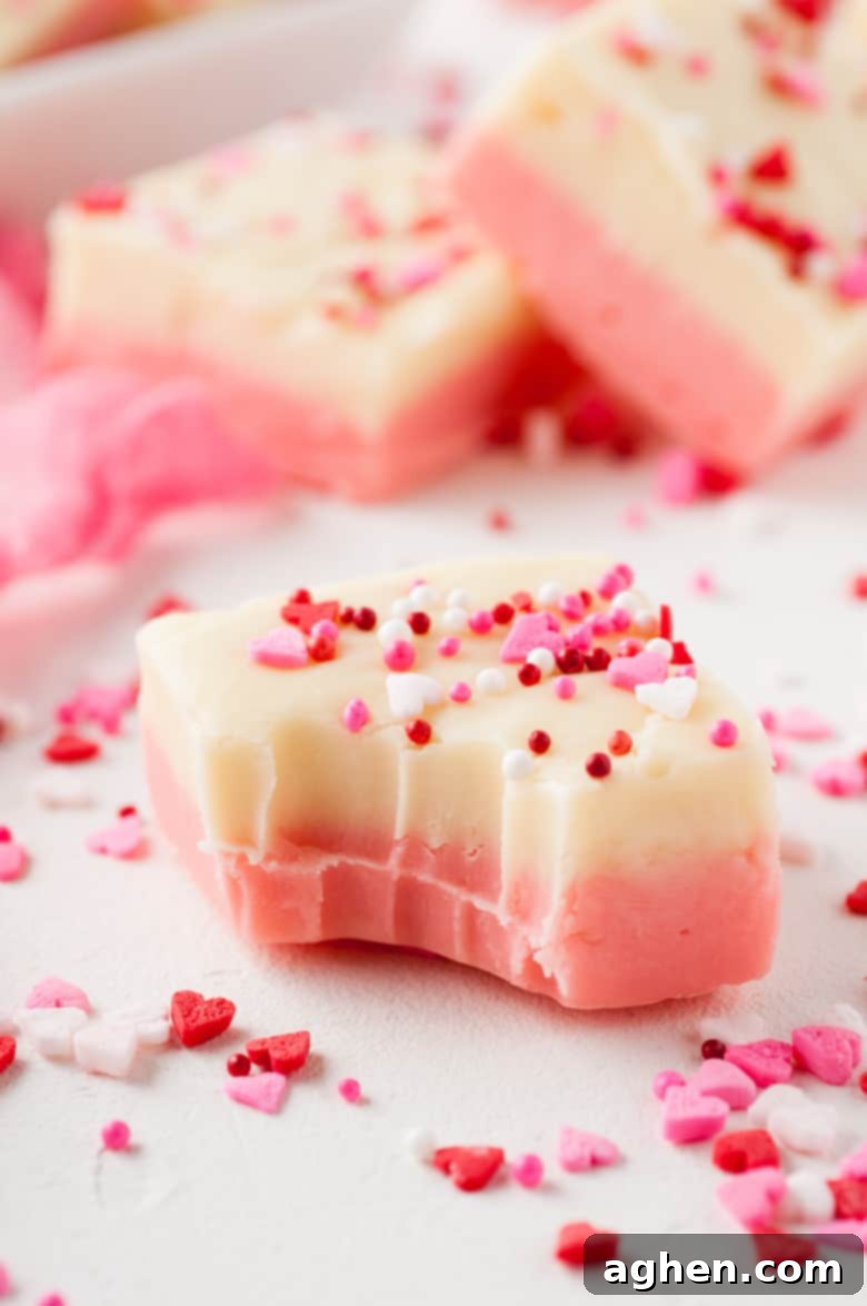 Square of creamy white chocolate Valentines fudge with a bite mark and heart sprinkles, showcasing its delightful texture and festive appearance.
