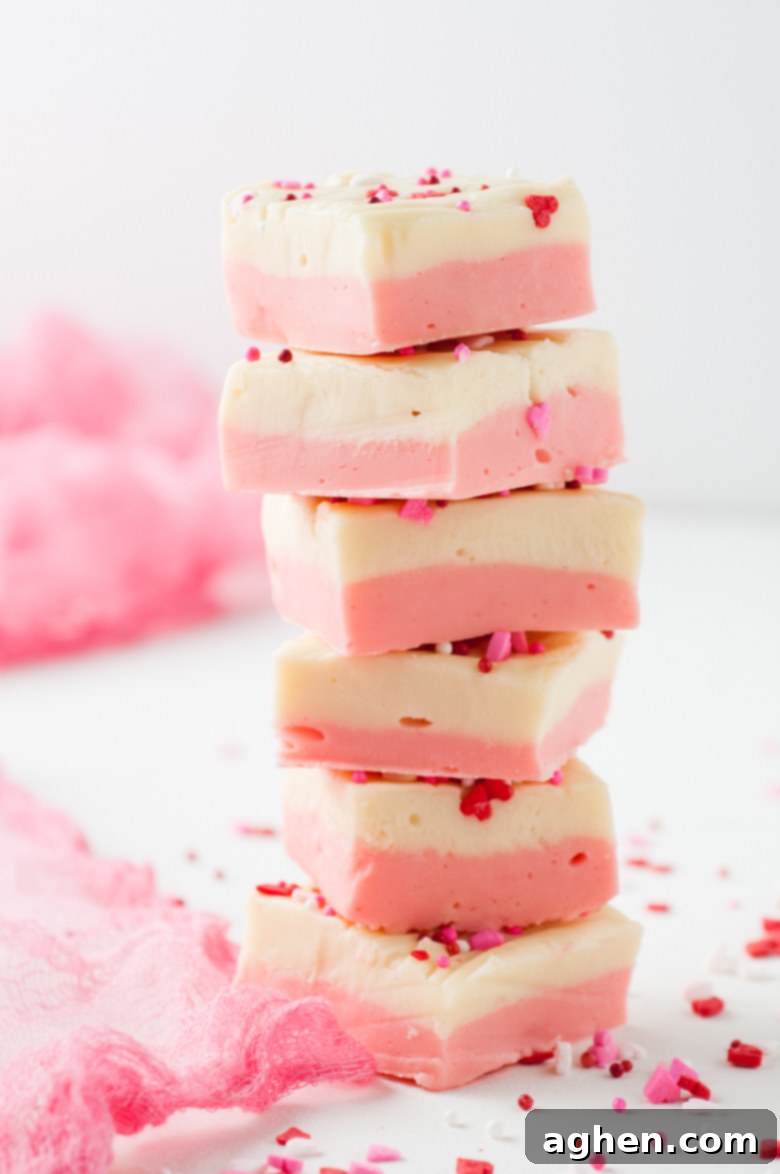 Six pieces of pink and white fudge stacked on top of each other to make a tower, showing off the beautiful layers and festive look.