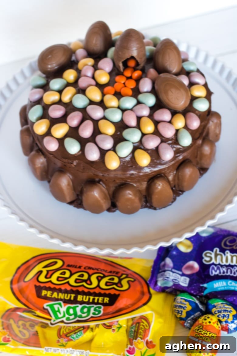 Delicious chocolate layer cake generously topped with an assortment of colorful HERSHEY'S Easter candies including Cadbury Eggs, REESE'S Eggs, and Shimmer Mini Eggs, ready for a festive celebration.