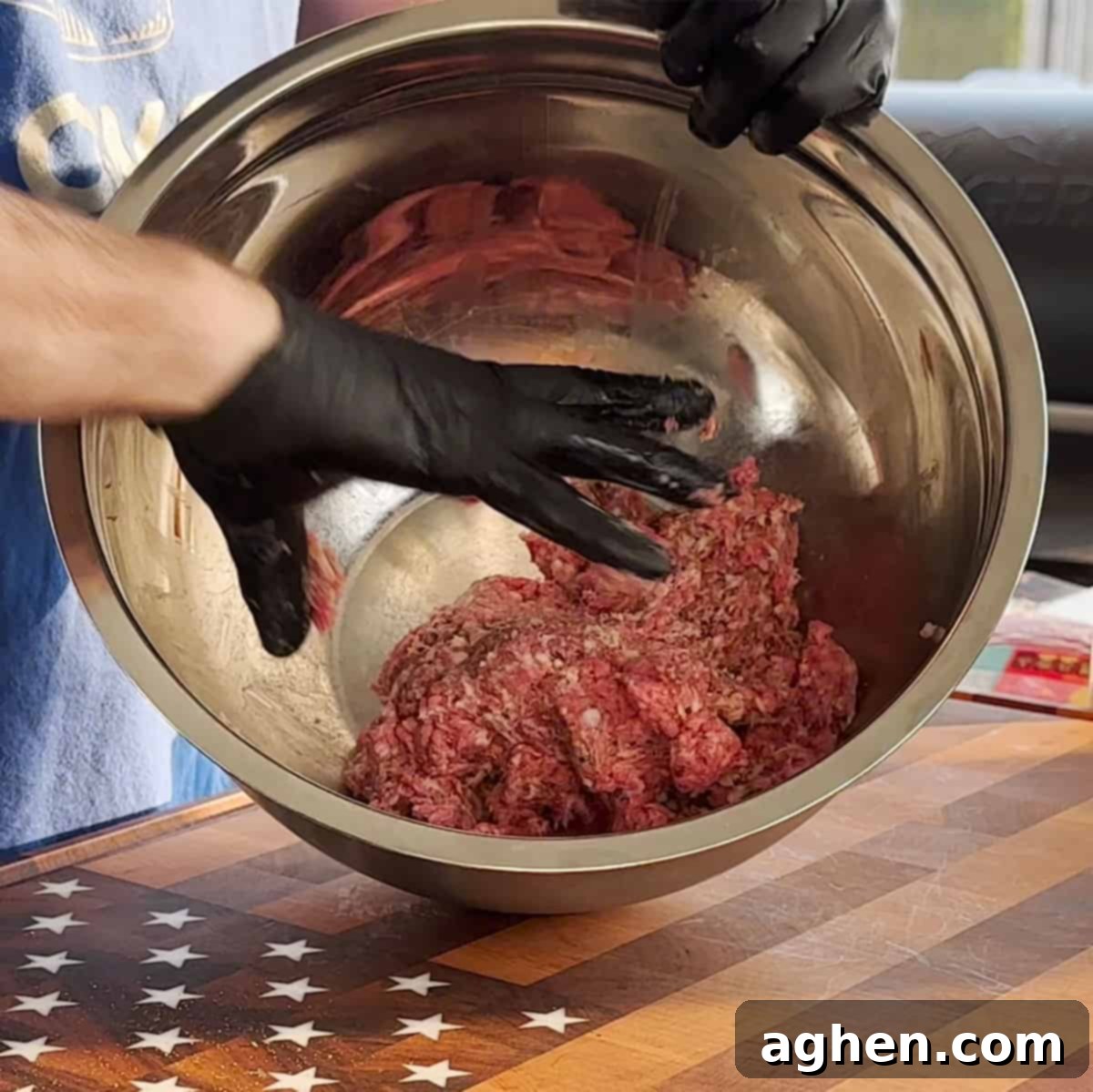 Hands mixing ground beef and sage pork sausage with seasoning in a large bowl