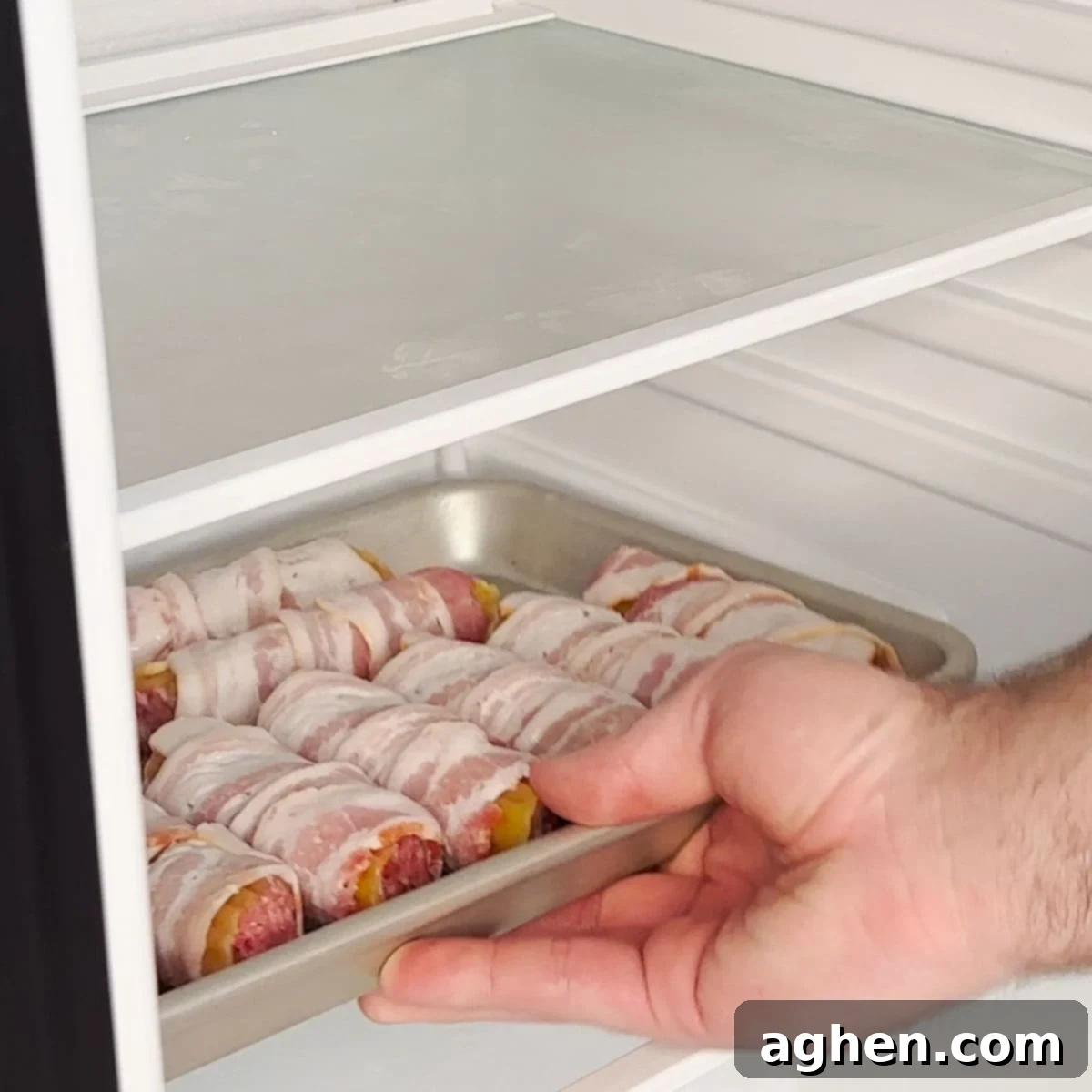 Bacon-wrapped shotgun shells arranged on a baking rack inside a refrigerator for overnight chilling