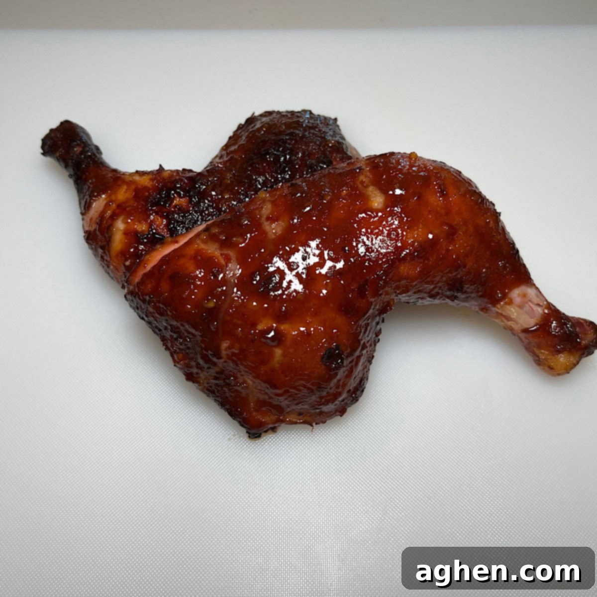 Honey glazed smoked chicken on white cutting board, perfectly cooked with a golden-brown crust.