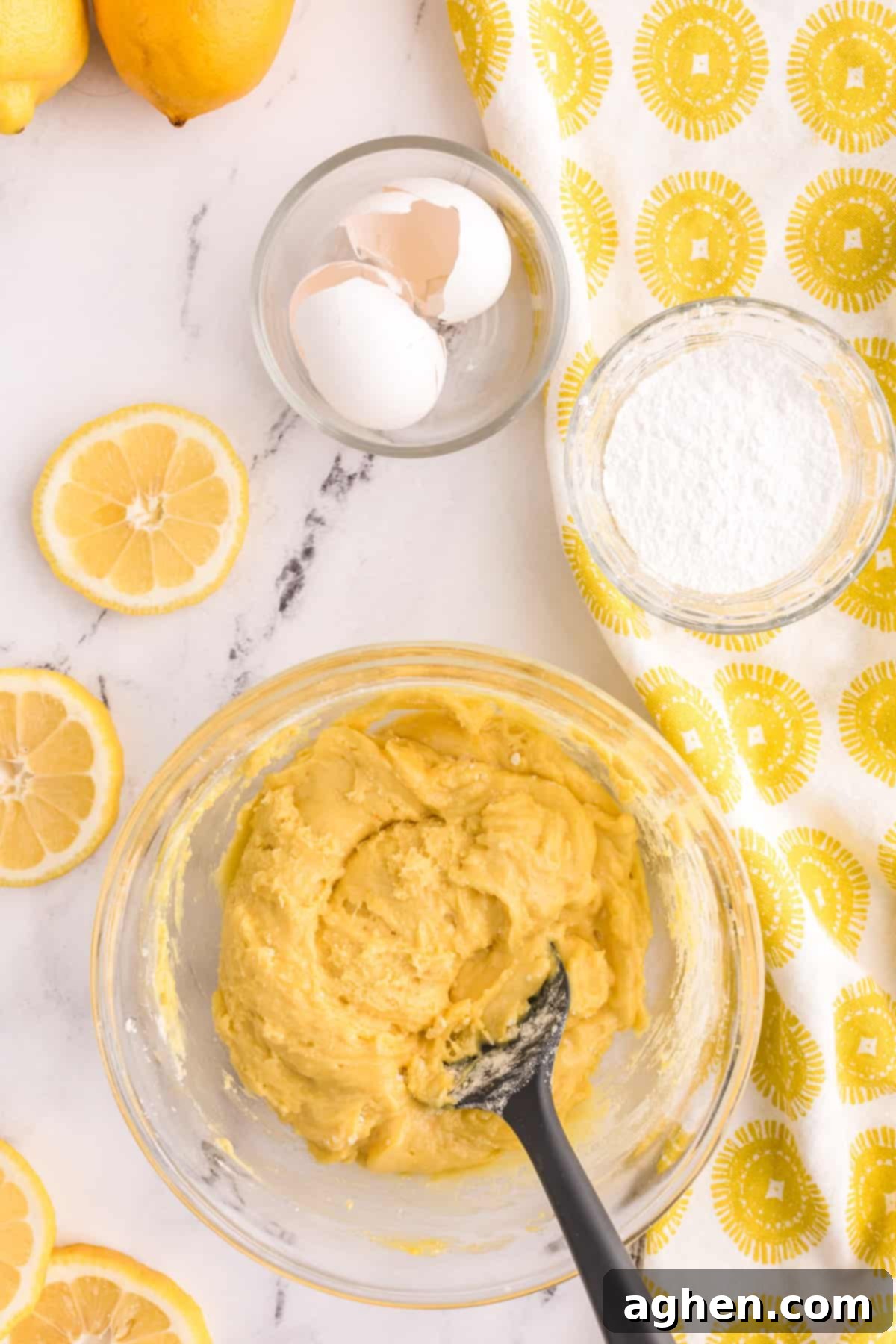 A bowl of sticky lemon cookie dough being mixed with a rubber spatula.