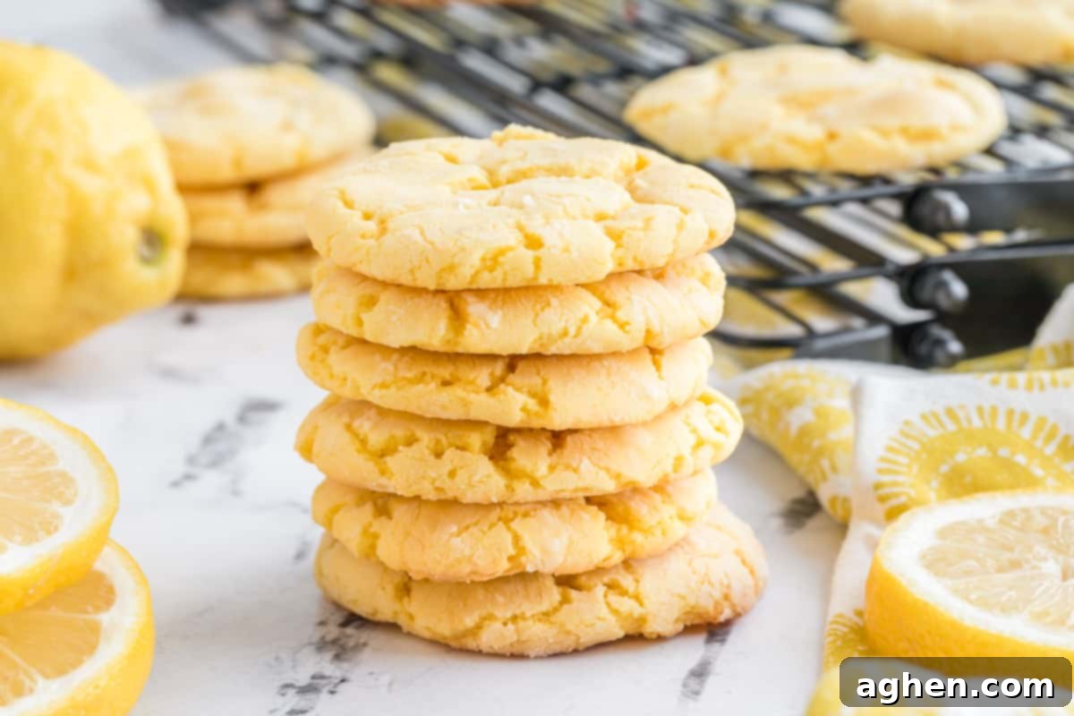 A stack of lemon crinkle cookies, with a wire rack and more cookies blurred in the background, showcasing their perfect texture.