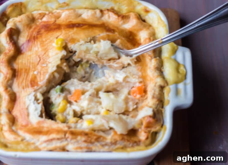 Chicken Pot Pie with flaky crust broken open to reveal creamy filling