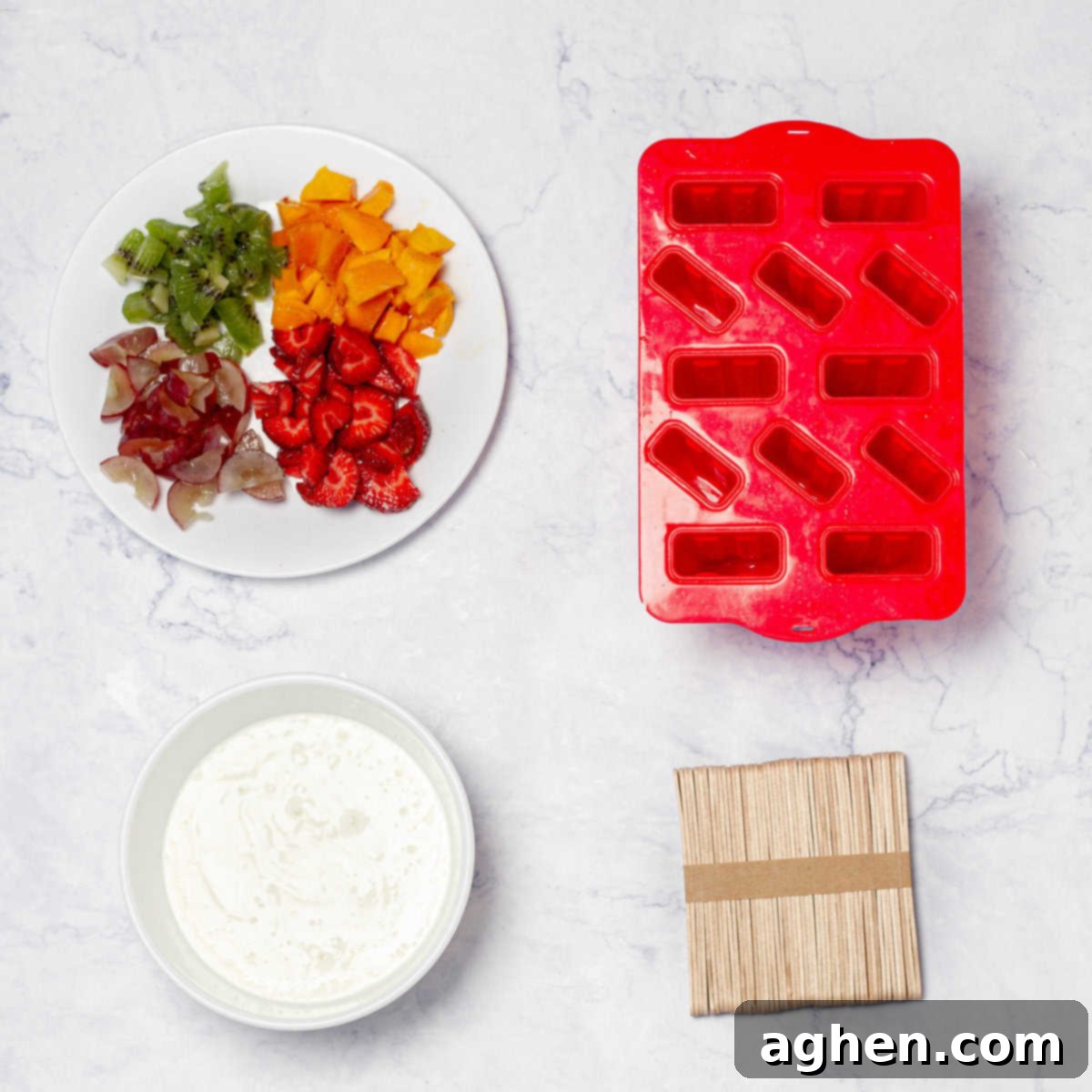 Your Family Will Crave These Healthy Yogurt & Fruit Ice Pops 3 Fruit and yogurt ice pop ingredients of chopped fruit and Greek yogurt in separate dishes next to popsicle molds and popsicle sticks.