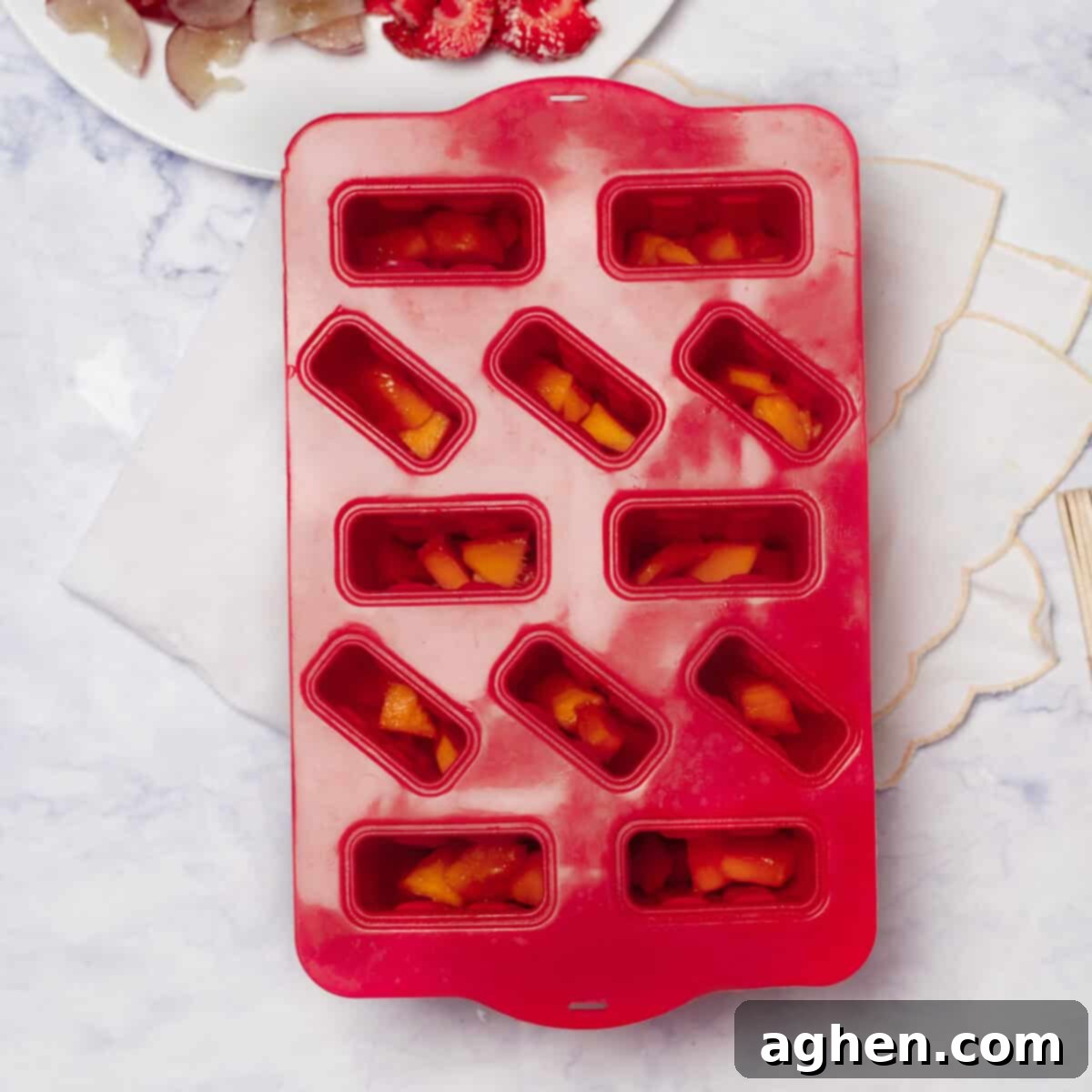 Your Family Will Crave These Healthy Yogurt & Fruit Ice Pops 4 Chopped strawberries added to the bottom of popsicle molds.