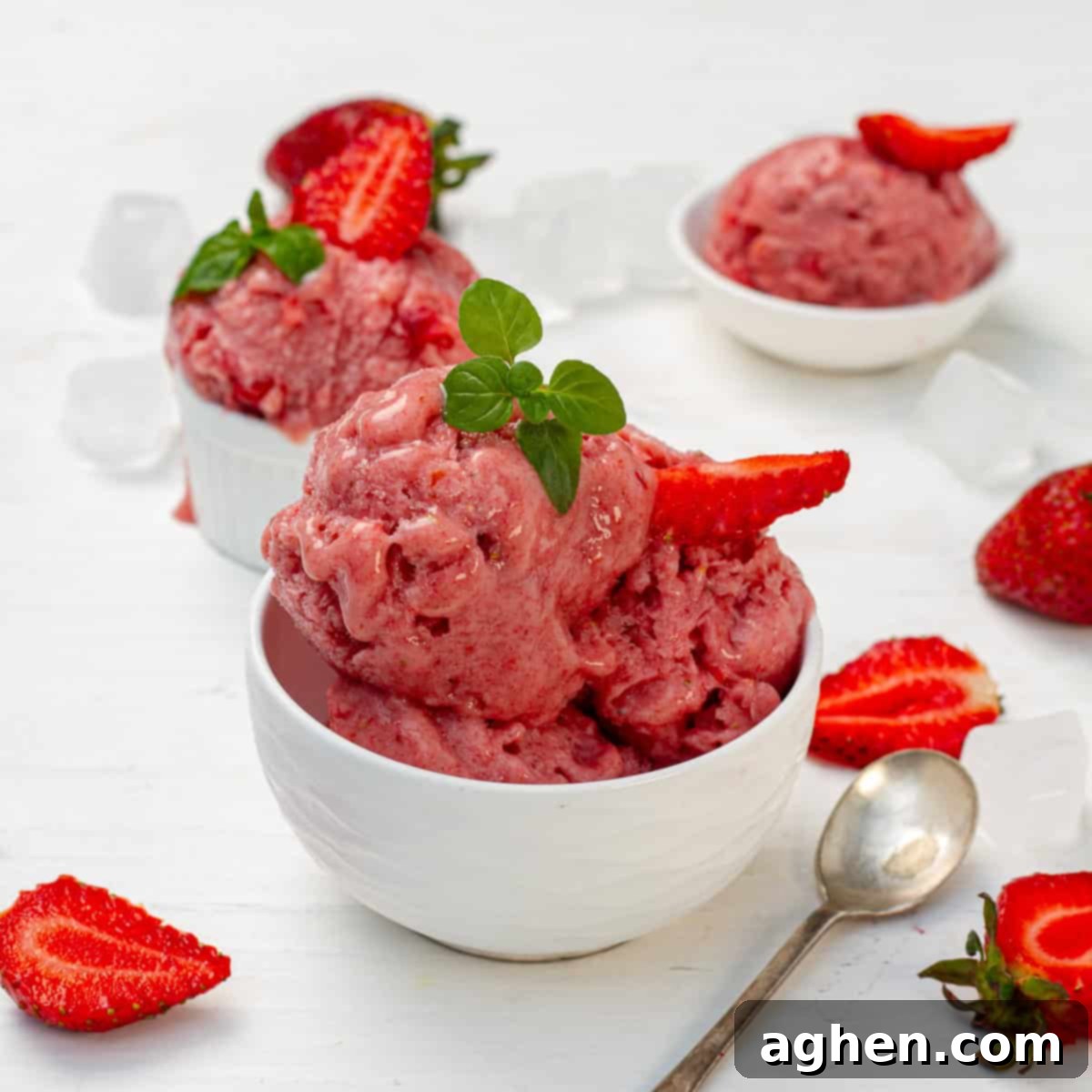 A beautifully scooped bowl of creamy Strawberry Banana Yogurt Ice Cream, garnished with fresh strawberry slices and a spoon resting on the side, inviting a delightful taste.