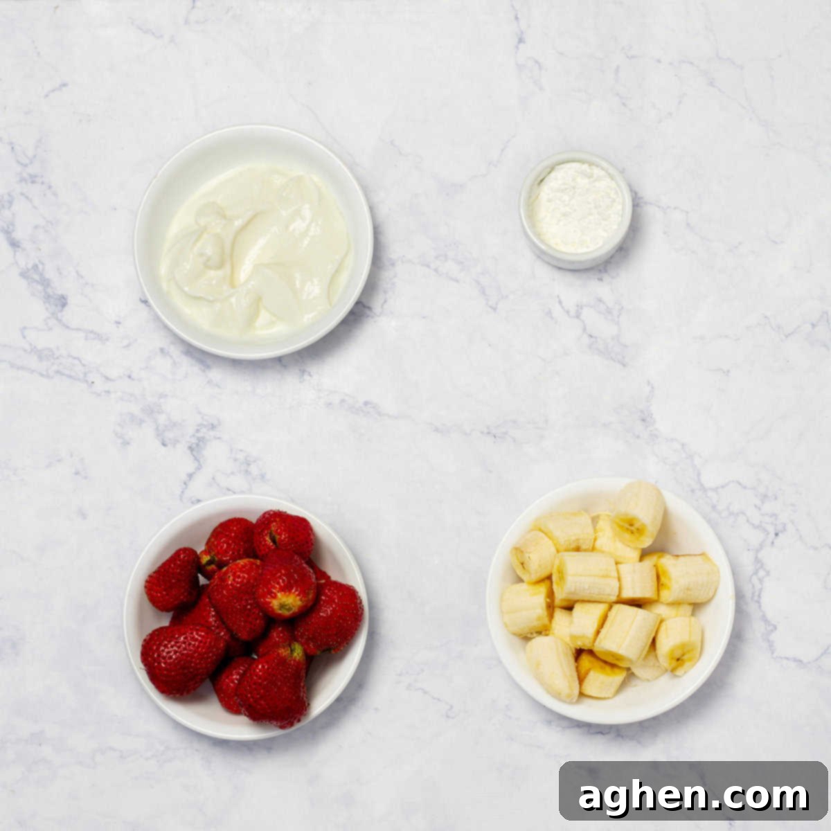 Carefully arranged ingredients for homemade ice cream, featuring creamy Greek yogurt, vibrant sliced strawberries, perfectly ripe sliced bananas, and a packet of Splenda sweetener, ready for blending.