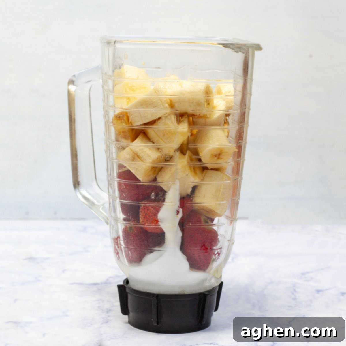 A vibrant close-up shot of sliced bananas and fresh strawberries alongside creamy yogurt, all placed within a blender, poised for transformation into delicious ice cream.