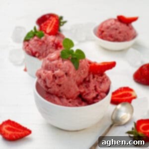 A perfectly scooped serving of homemade Strawberry Banana Yogurt Ice Cream in a small bowl, garnished with fresh strawberry slices, emphasizing its creamy texture.