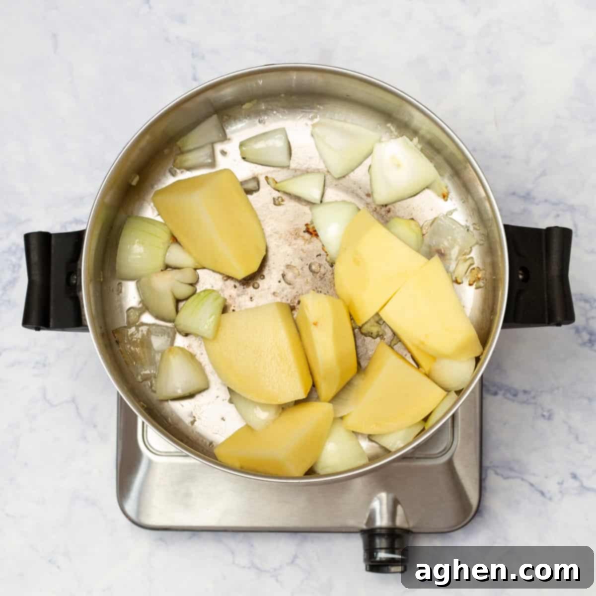 Onions and potatoes sauteing in a pan. 