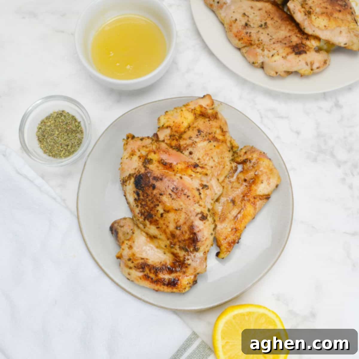Sizzle Your 4th: Essential Blackstone Recipes for a Spectacular Celebration 3 Small plate with two cooked chicken thighs. To the side sit a small bowl of honey, a bowl of oregano, a sliced lemon, a white napkin and off to the side a plate of chicken.