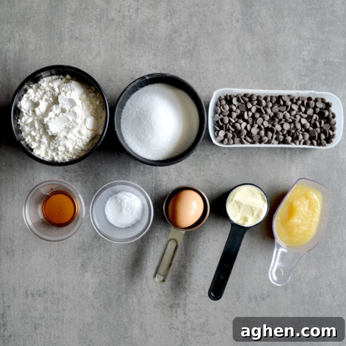 Arrangement of ingredients needed for making healthy chocolate chip cookies, including applesauce and sugar substitute, clearly laid out on a kitchen counter.