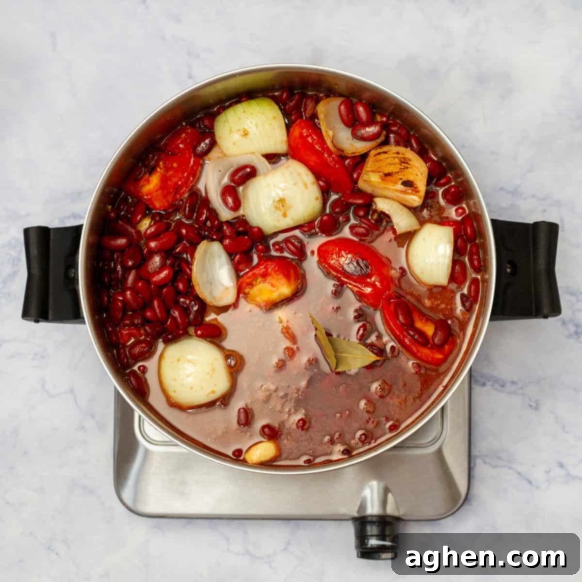 Sauteed aromatics, beans, and spices simmering in a pot of broth. 