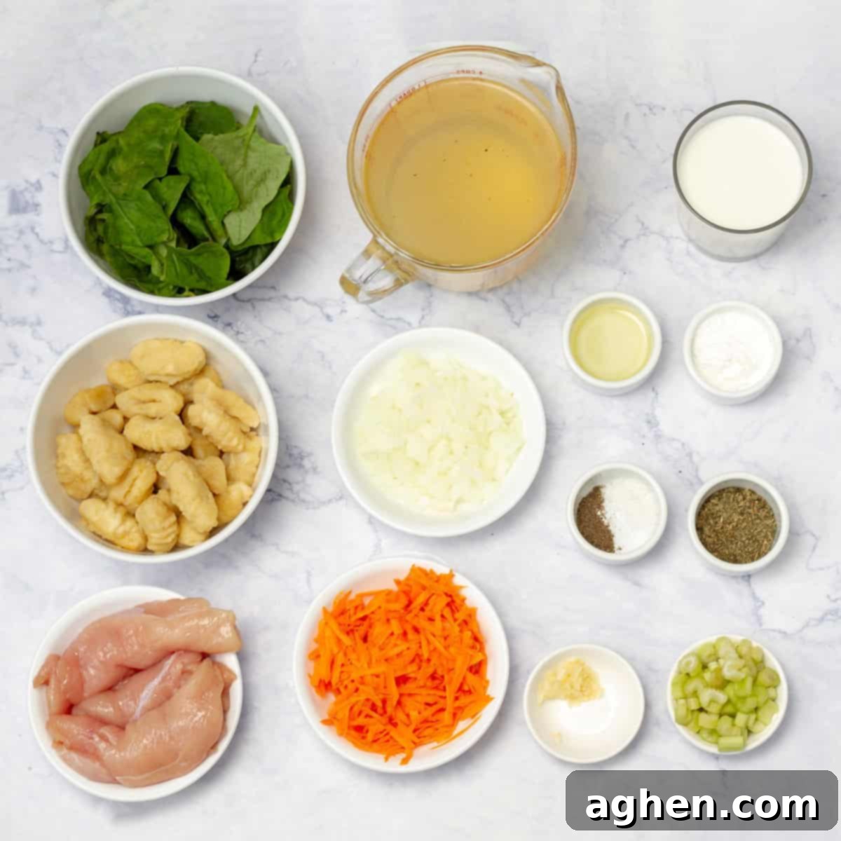 Fresh ingredients for Chicken Gnocchi Soup laid out on a kitchen counter: chicken breast, spices, garlic, onion, carrots, celery, gnocchi, chicken broth, thyme, skim milk, cornstarch, and spinach.