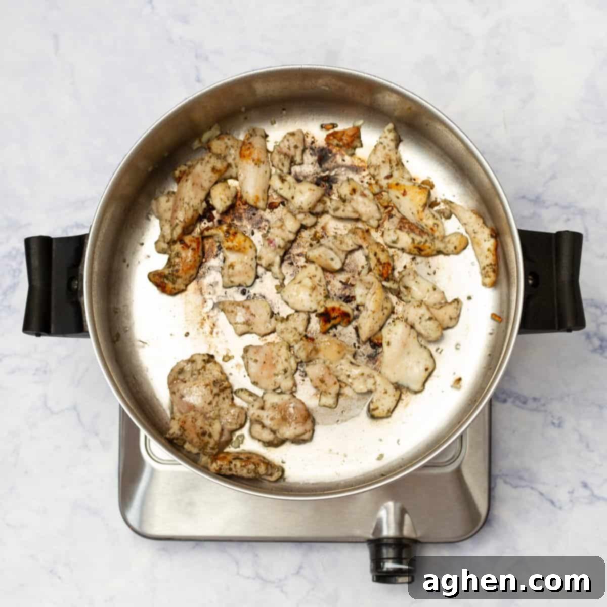 Cubed chicken breast cooking in a hot pan, browning nicely.