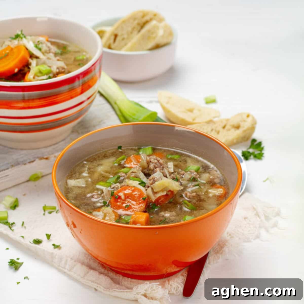Brothy and satisfying egg roll soup in an orange bowl, garnished with fresh green onions.