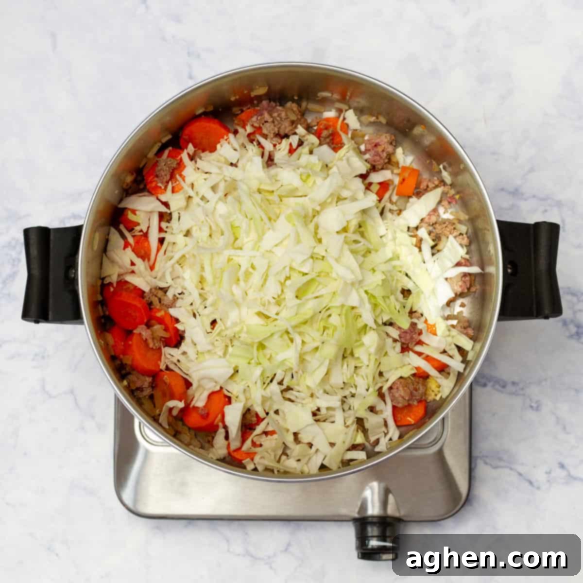 All the vibrant vegetables including shredded cabbage, sliced carrots, and onions, along with perfectly browned ground beef, enthusiastically sauteing together in a large pan, creating a rich base for the soup.