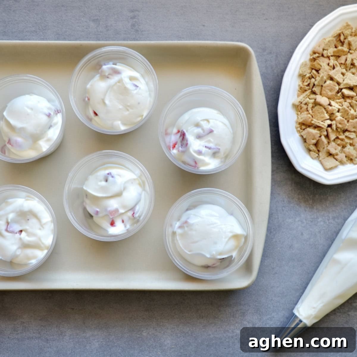 Weight Watchers' Legendary Cheesecake Fluff 6 Individual dessert cups being filled with strawberry cheesecake fluff, ready for garnishing.