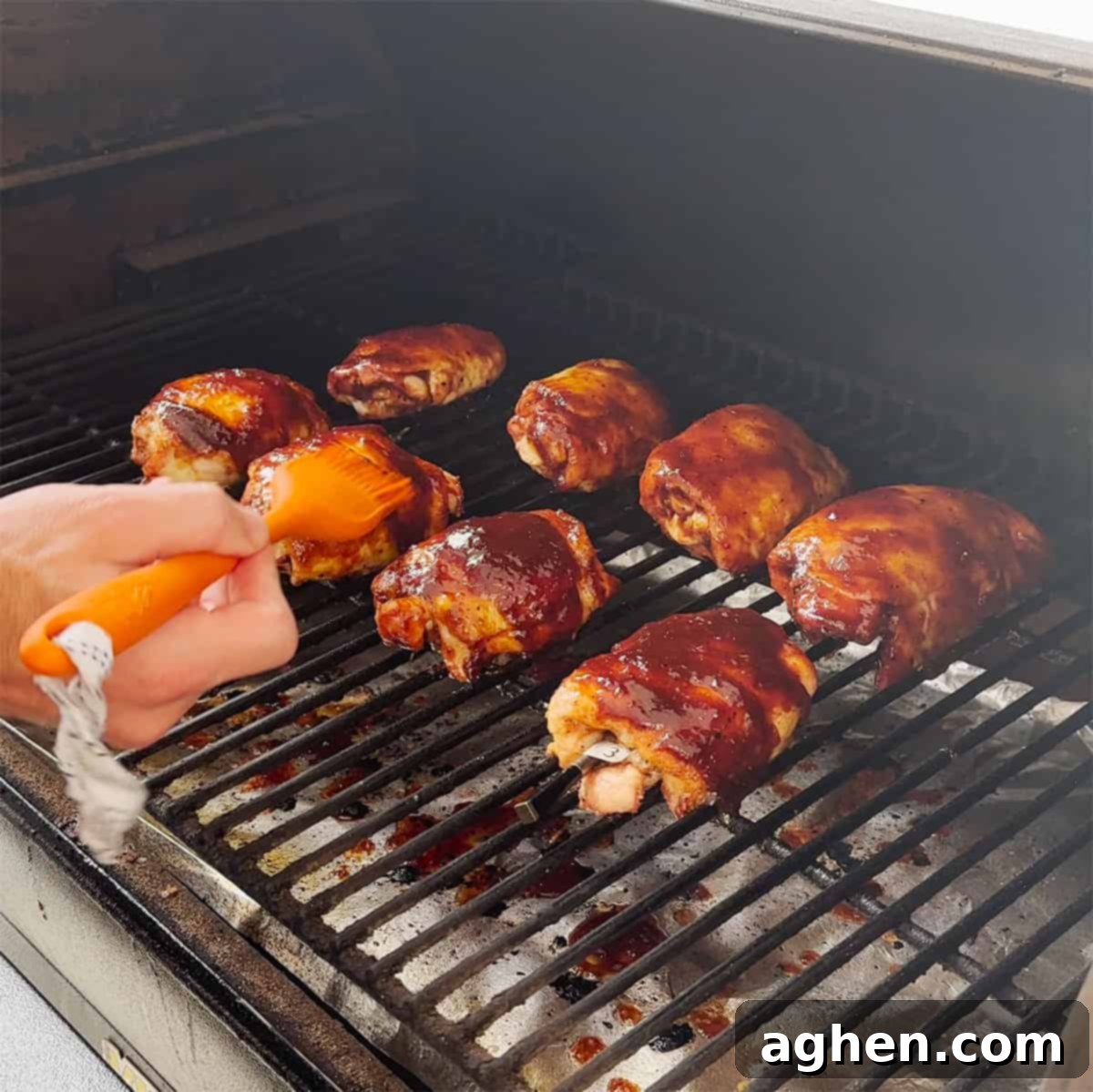 Glazed smoked chicken thighs on the grill, caramelizing to perfection.