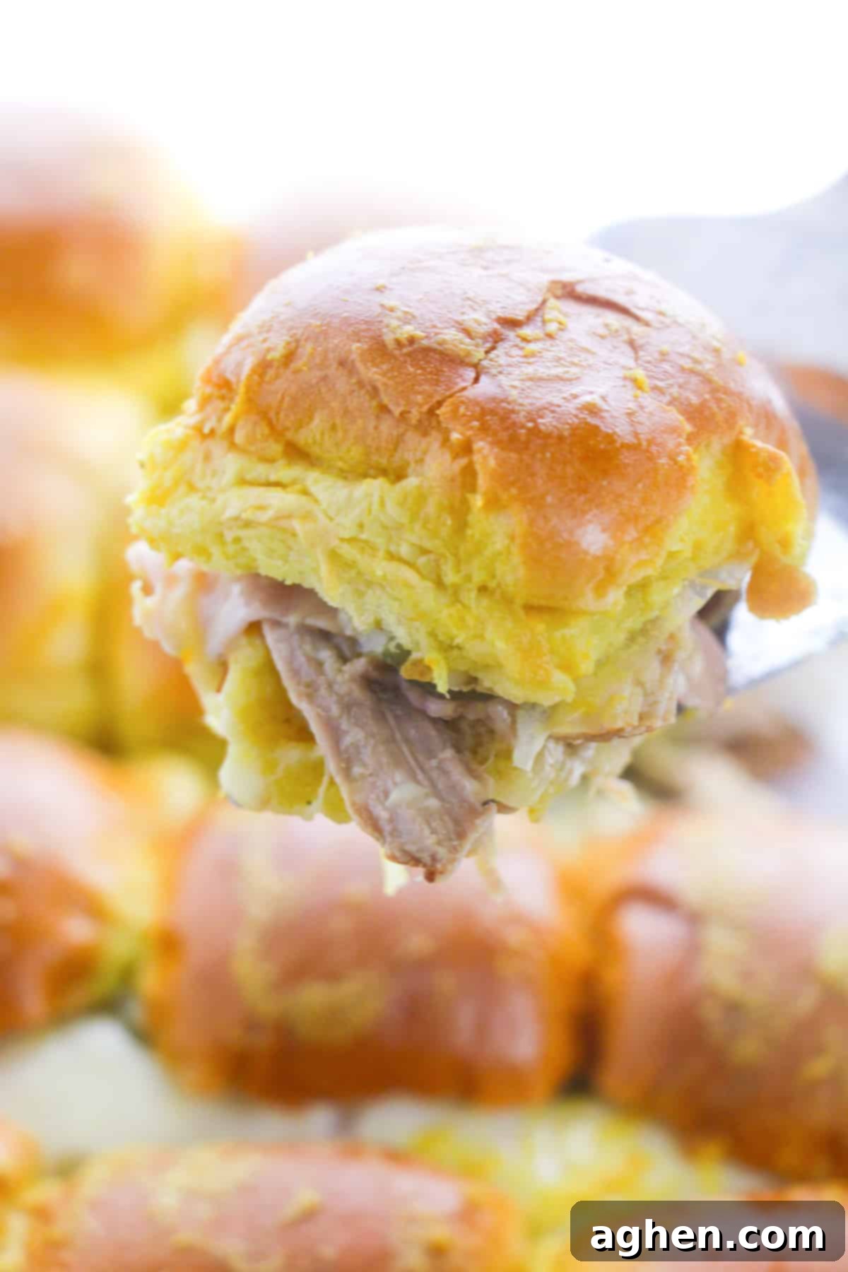 Spatula pulling a slider up out of baking dish.