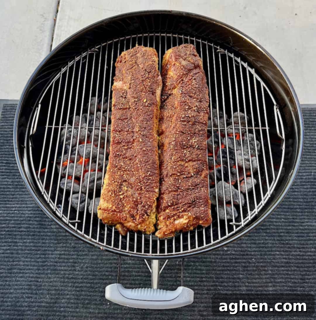 Baby back ribs smoking on a Weber Kettle grill