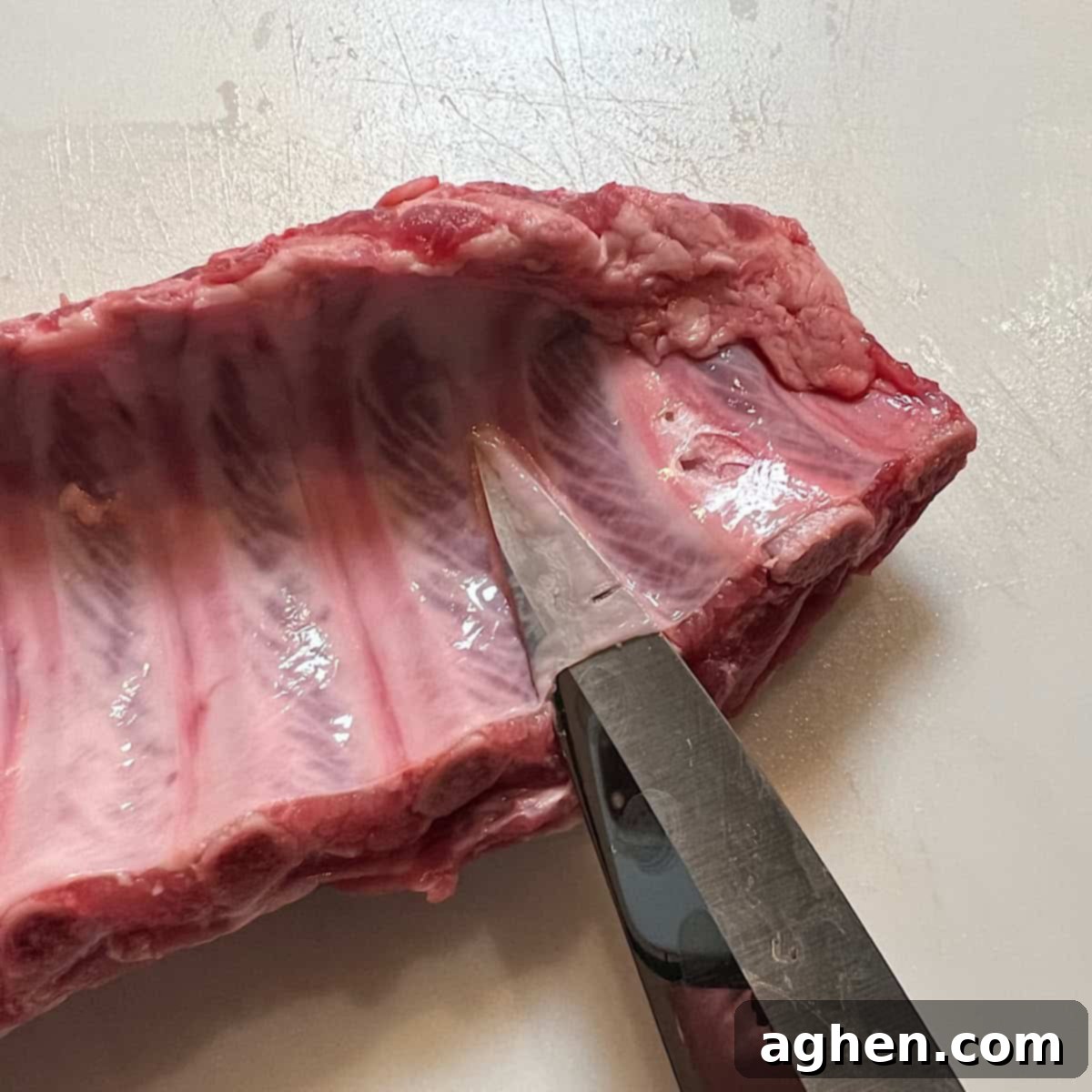 Sharp knife separating pork membrane from ribs