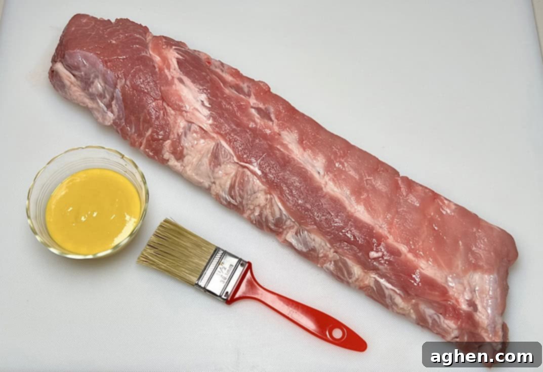 Brushing yellow mustard onto baby back ribs