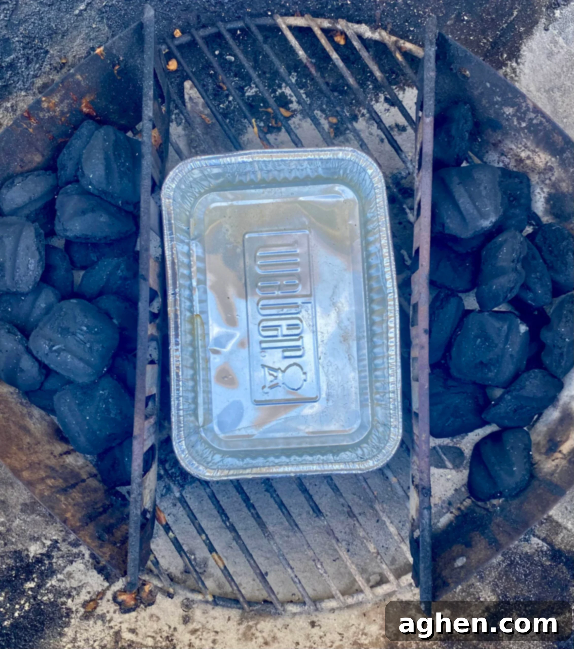 Water pan placed in a Weber charcoal grill for moisture and temperature regulation during cooking.