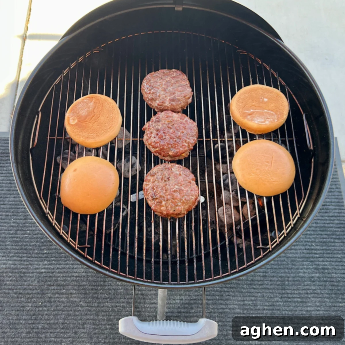 Three Juicy Lucy burgers grilling over indirect heat with brioche buns toasting