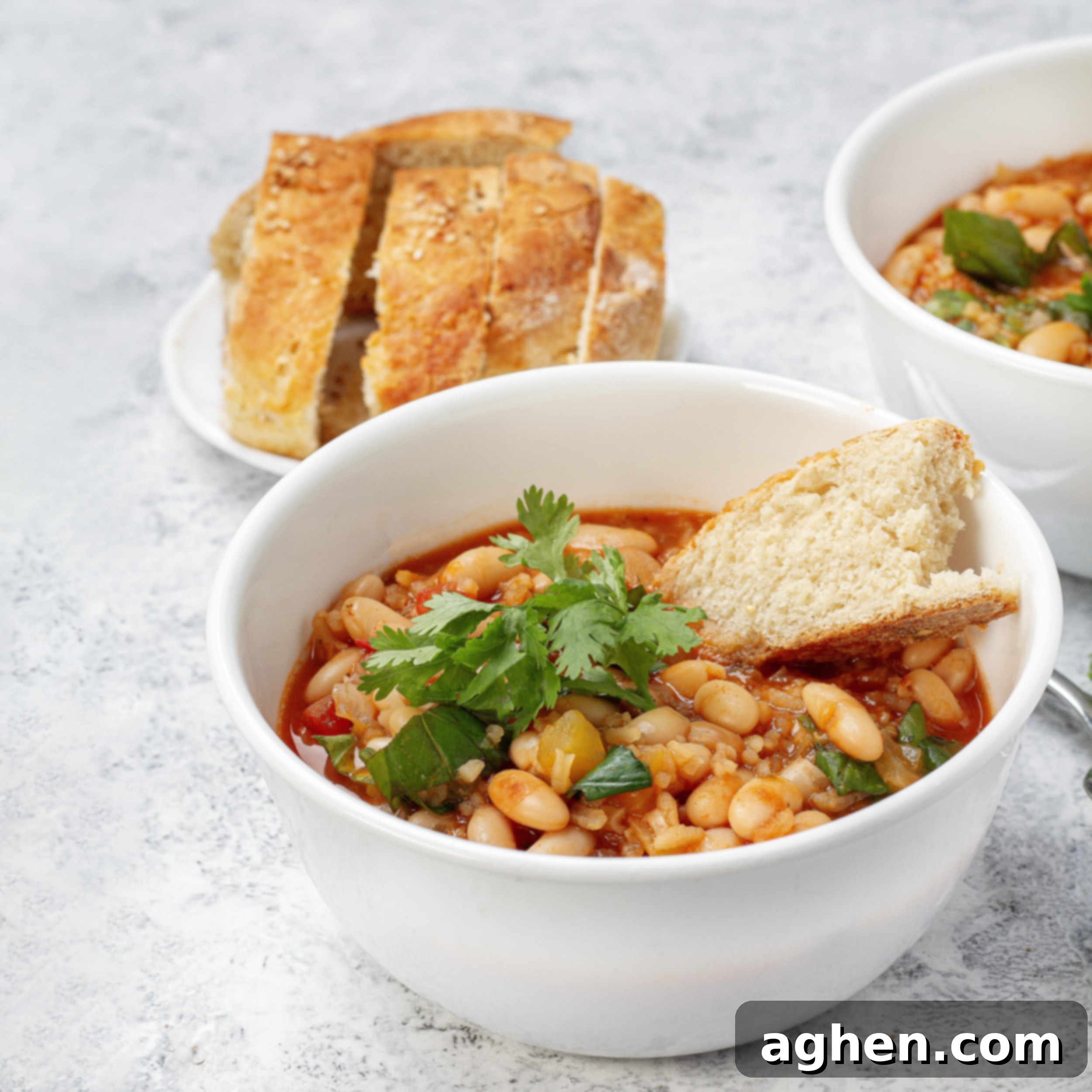Chunky and delicious Mediterranean White Bean Soup in a bowl with a piece of bread and parsley garnish.