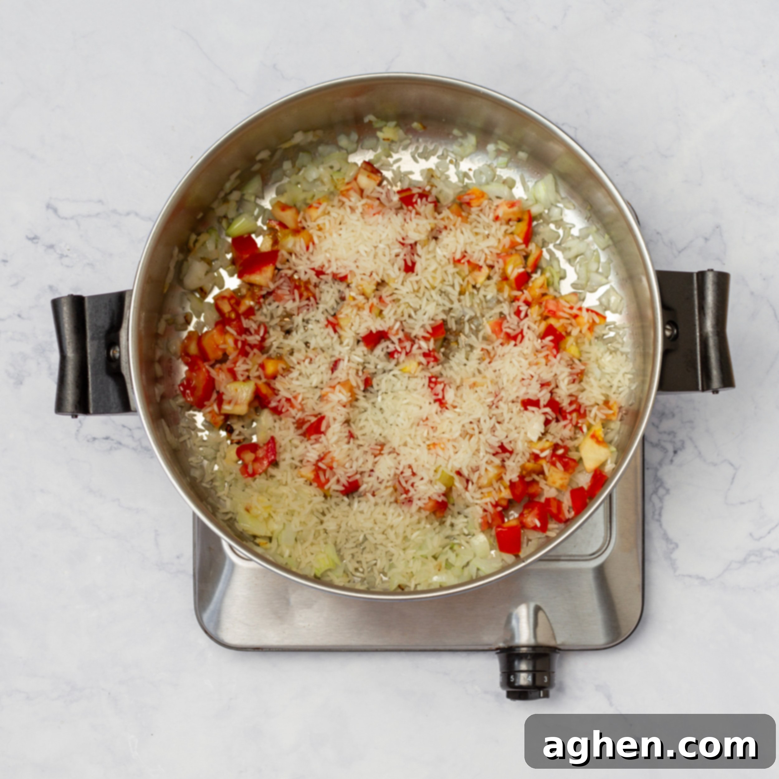 Aromatics and tomatoes sauteing in a pot. 