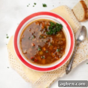 Lentil Cabbage Soup in a bowl with a spoon and a piece of bread.