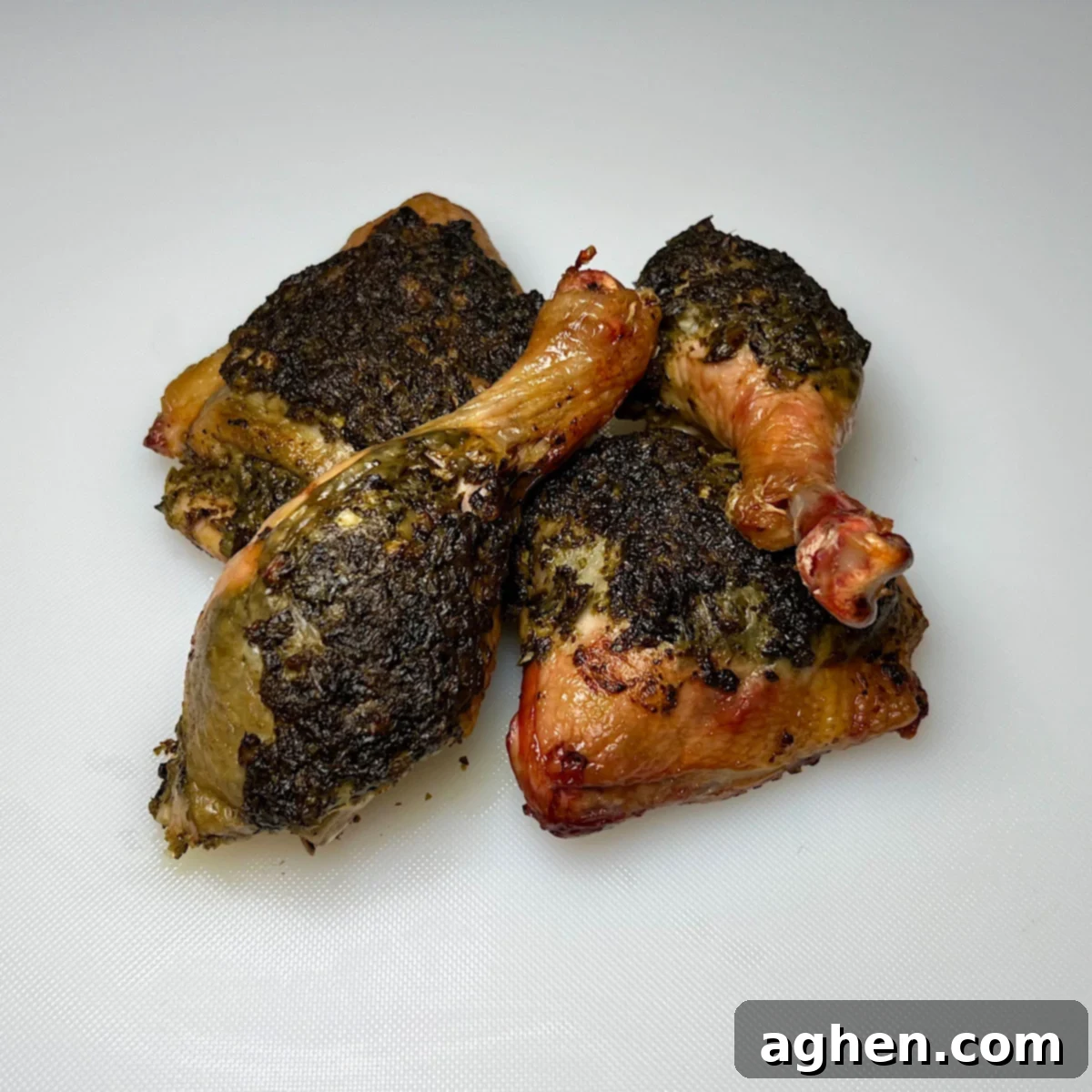 Four pieces of perfectly grilled pesto chicken leg quarters, ready to serve.