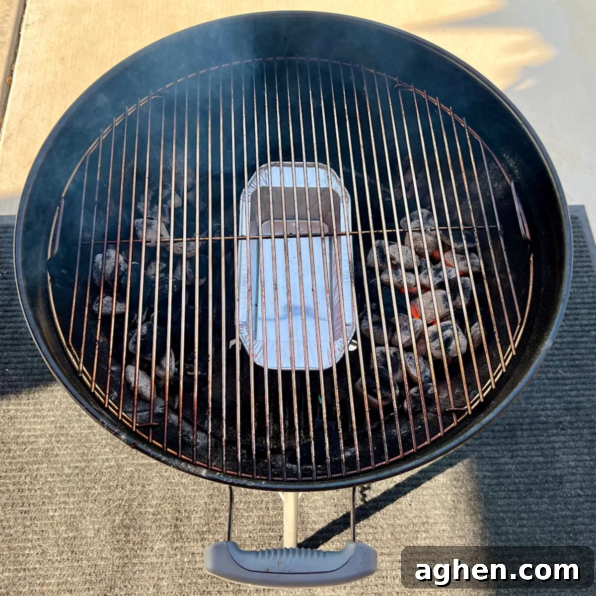 Disposable aluminum drip pan filled with water placed on the charcoal grate.